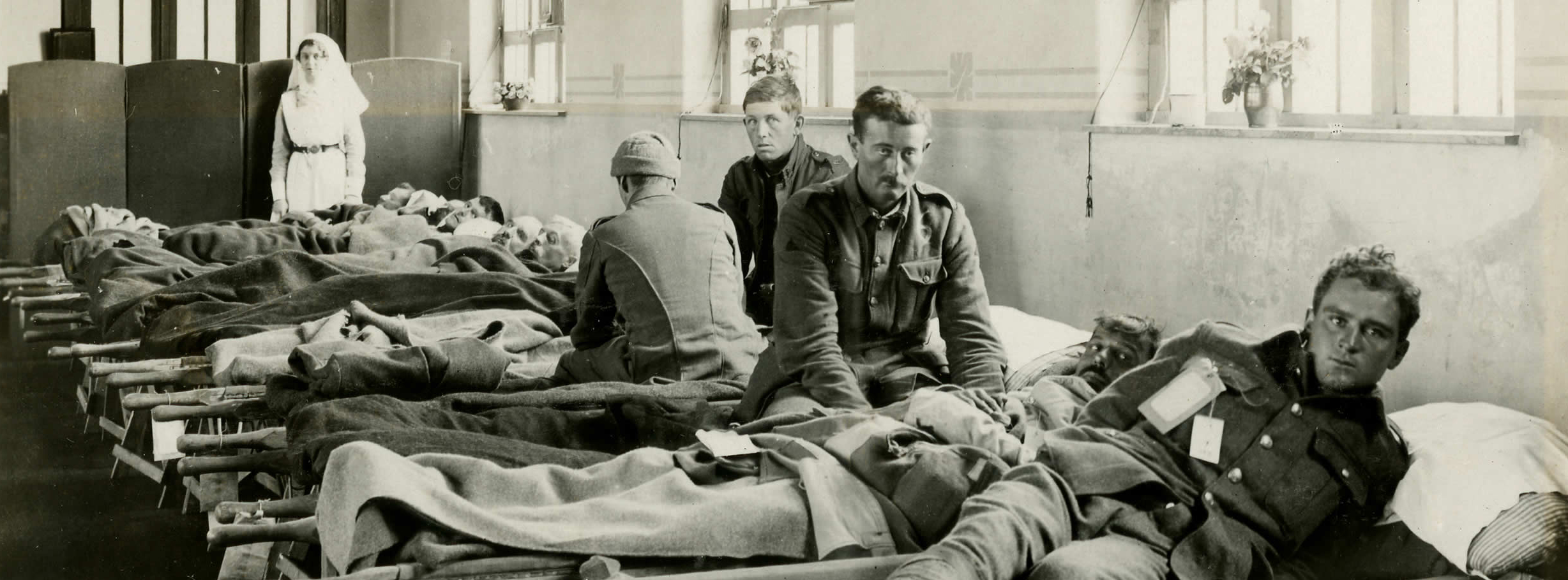 view of several men in uniforms and in hospital beds with a nurse in the background
